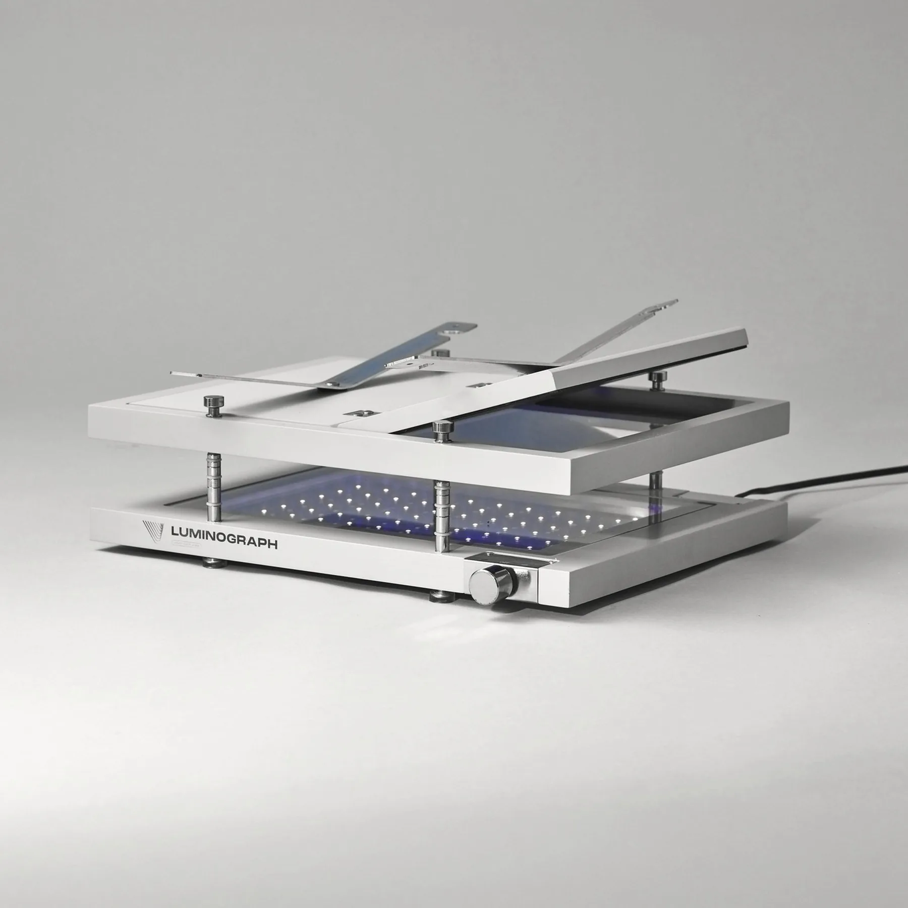 Luminograph A4, presse ouverte : plateau relevé sur ses colonnes, bras levés, LED UV allumées