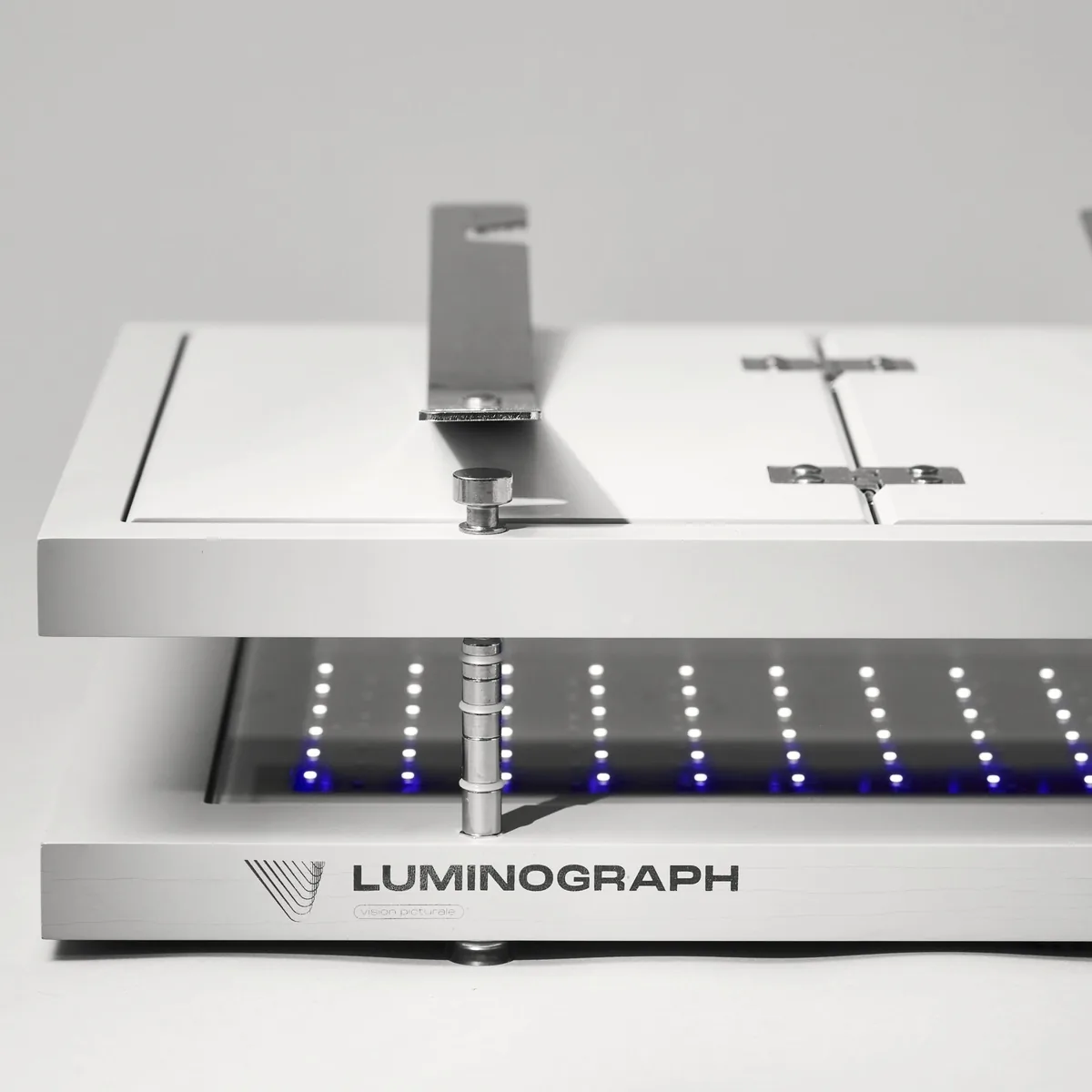 Luminograph A4, gros plan d’un bras de presse sur sa colonne, au-dessus de la grille de LED UV