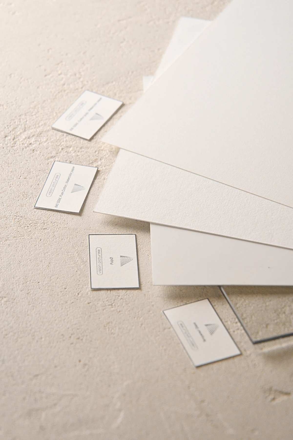 Feuilles de papier aquarelle et étiquettes posées sur le sol de l’atelier